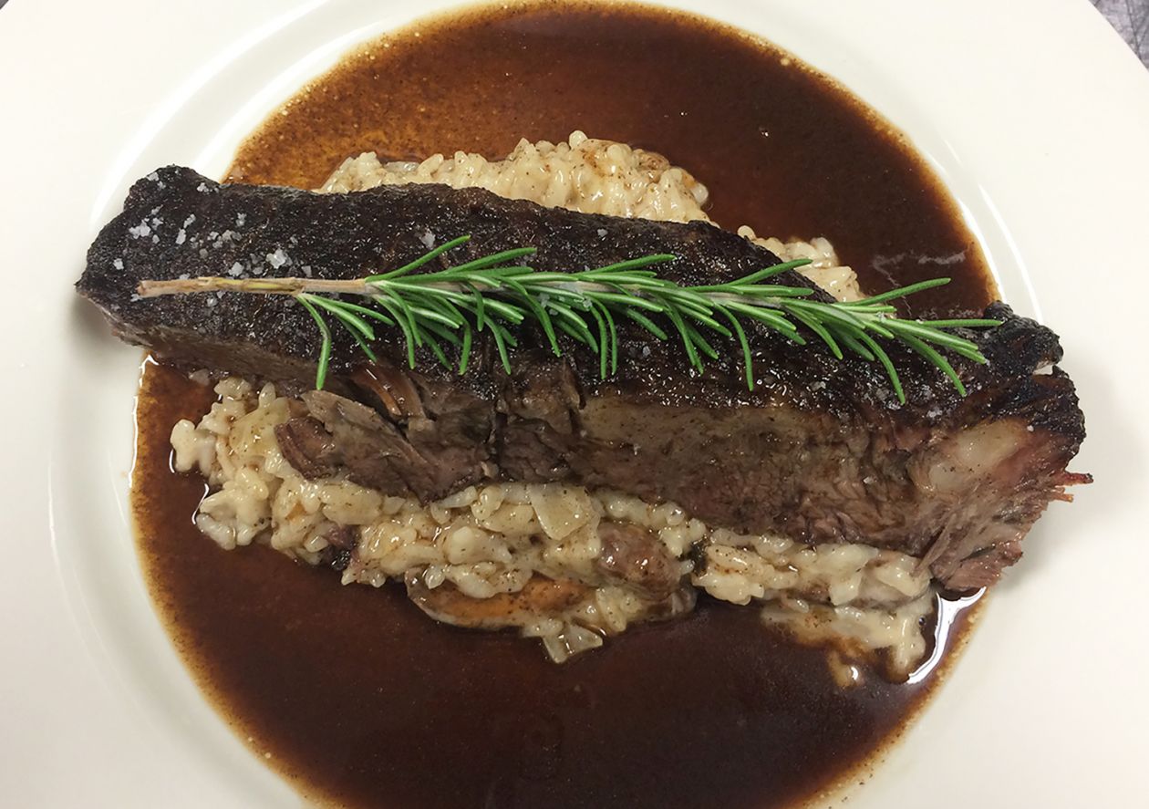 Bistro steak over mushroom risotto garnished with rosemary