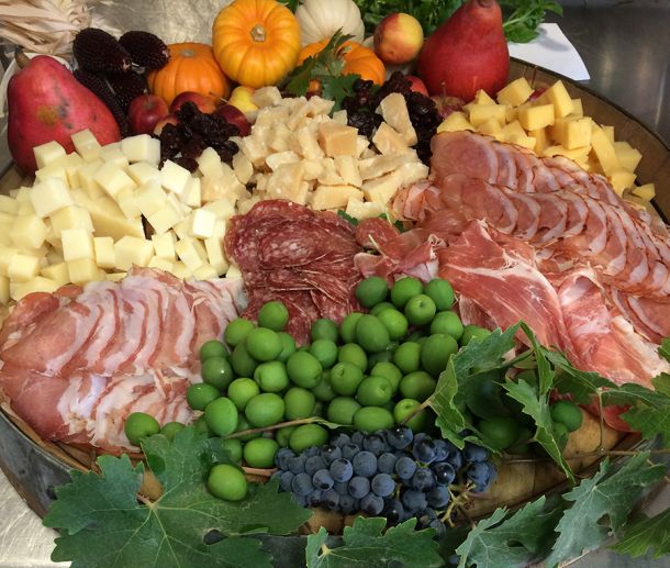 meat and cheese board with grape leaves and seasonal decorations